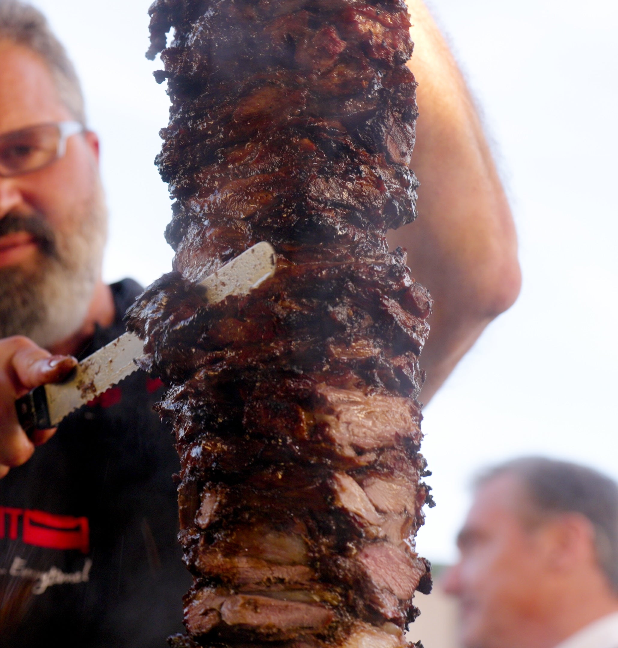 Person carving meat from a rotisserie 
